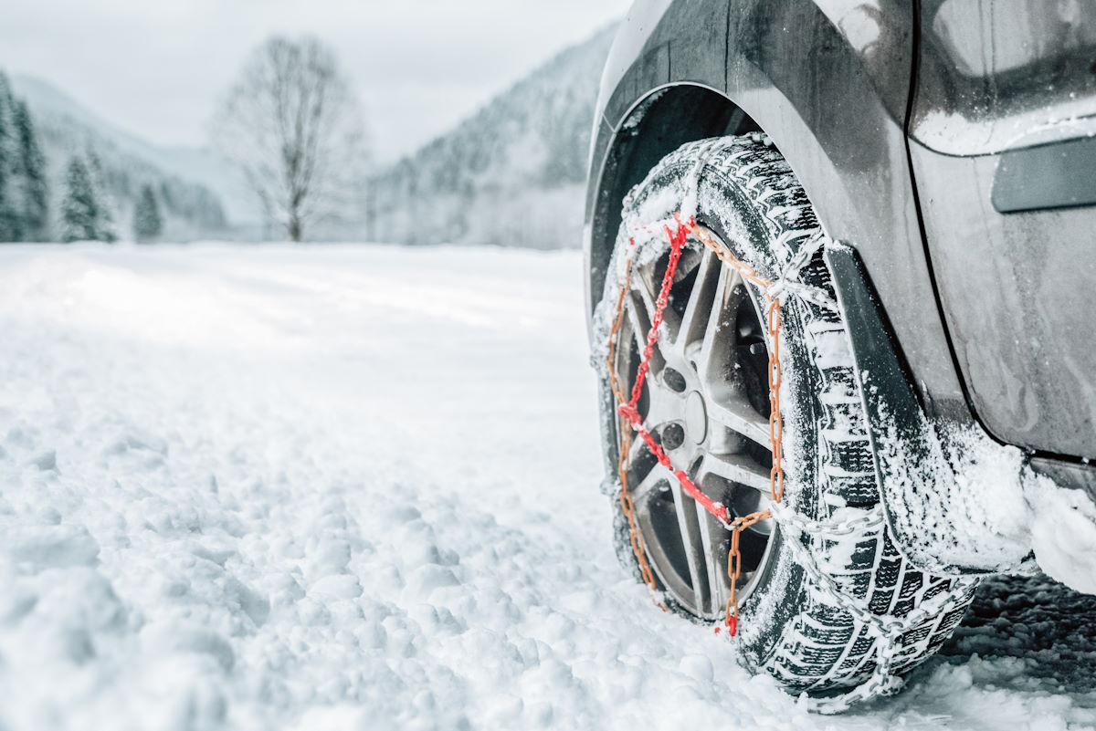 Auto mit montierten Schneeketten in Winterlandschaft